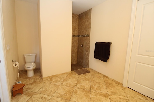 bathroom featuring a tile shower, toilet, and tile patterned floors