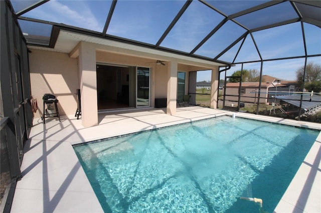 outdoor pool with a patio area, a lanai, and a ceiling fan