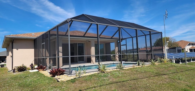 rear view of property with an outdoor pool, a lanai, a lawn, and stucco siding