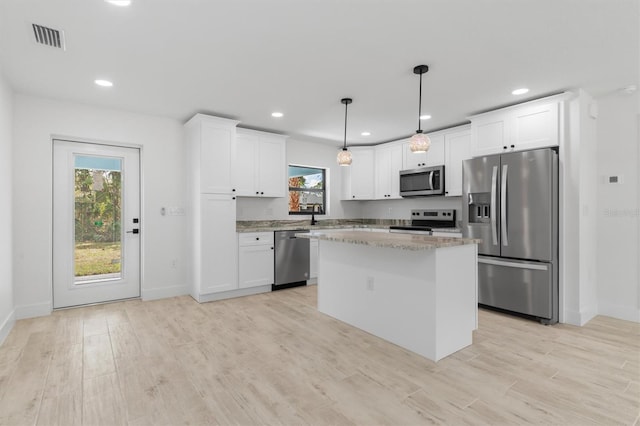 kitchen featuring hanging light fixtures, appliances with stainless steel finishes, white cabinetry, and a center island