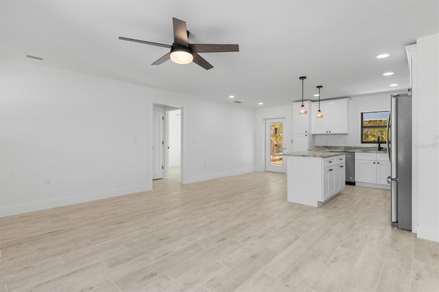 kitchen with white cabinets, open floor plan, appliances with stainless steel finishes, a center island, and pendant lighting