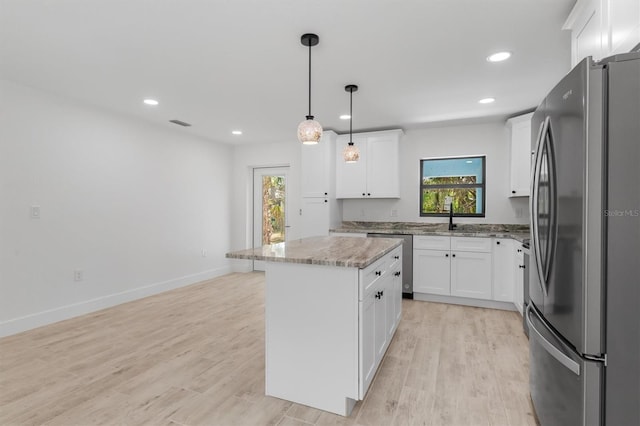 kitchen featuring stainless steel appliances, hanging light fixtures, white cabinetry, and a center island