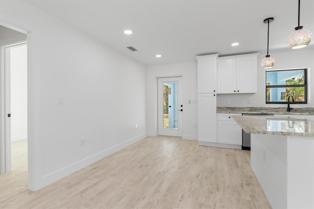 kitchen featuring dishwashing machine, light stone counters, decorative light fixtures, white cabinetry, and a sink