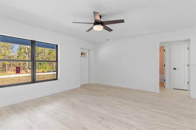 spare room featuring light wood-style floors, ceiling fan, and baseboards