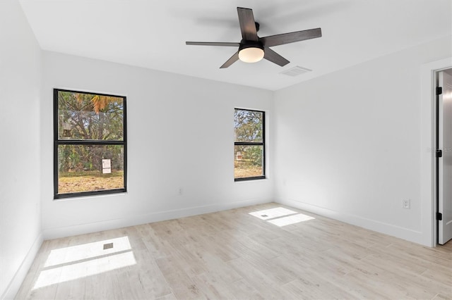 empty room featuring a ceiling fan, light wood-type flooring, visible vents, and baseboards