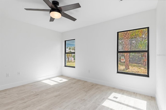 spare room with a ceiling fan, light wood-style flooring, and baseboards