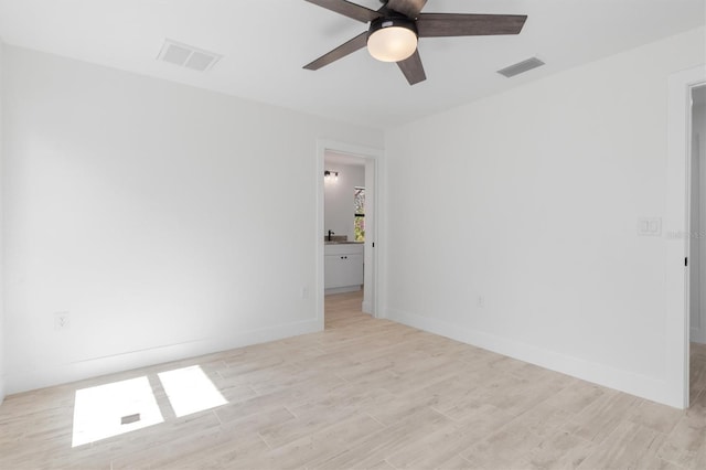 empty room featuring light wood-type flooring, visible vents, and baseboards