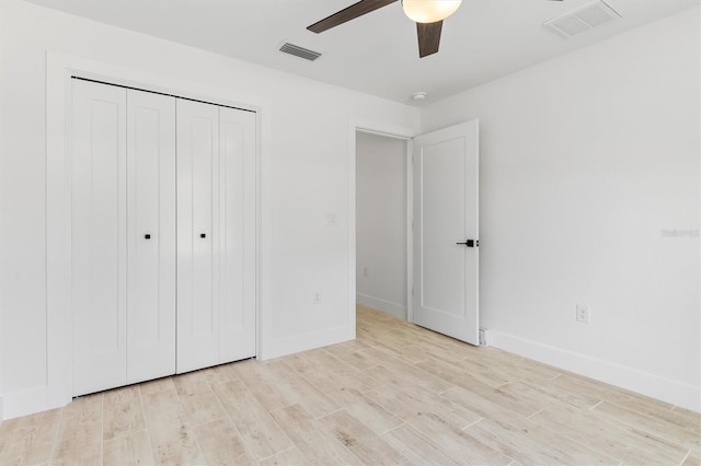 unfurnished bedroom featuring baseboards, light wood-style flooring, visible vents, and a closet