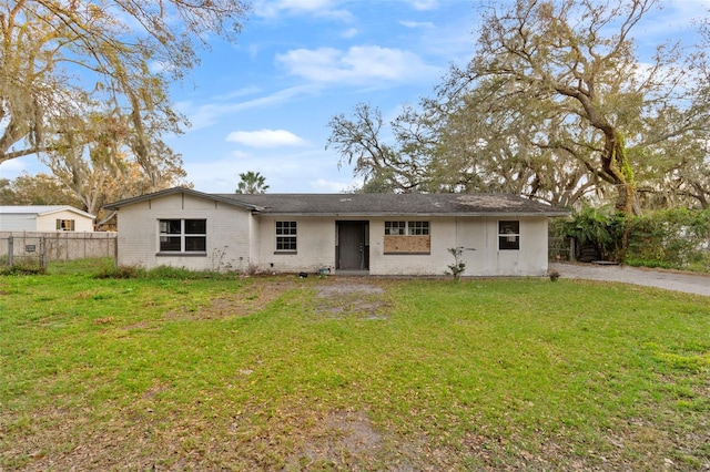 view of front facade with a front yard, brick siding, and fence