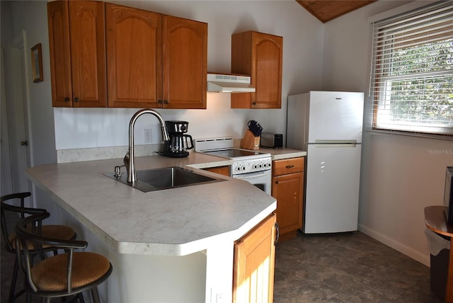 kitchen featuring a breakfast bar area, under cabinet range hood, white appliances, a sink, and light countertops