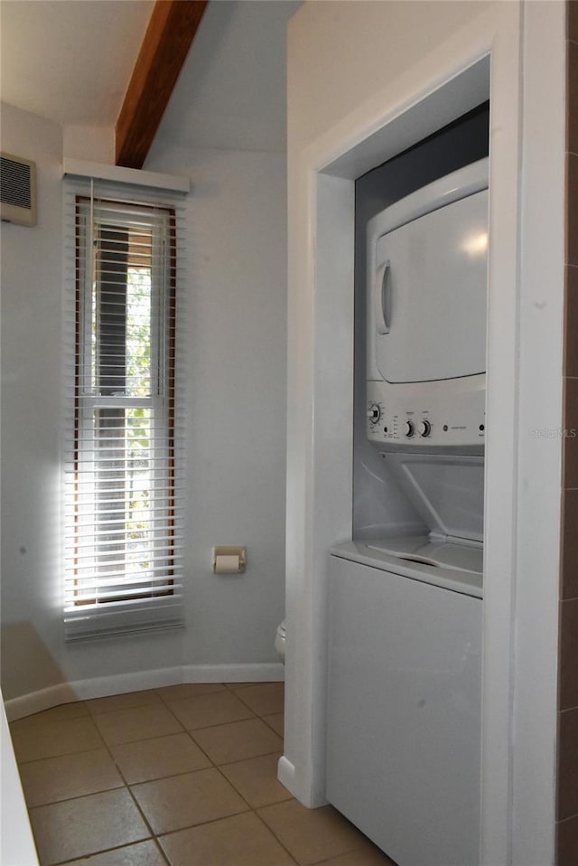 laundry area with laundry area, stacked washer and clothes dryer, baseboards, and light tile patterned floors