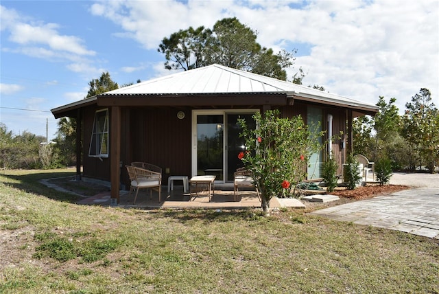 back of property with a patio area, metal roof, and a yard