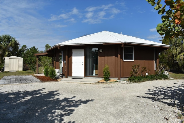 view of front of house featuring metal roof, a storage unit, and an outdoor structure