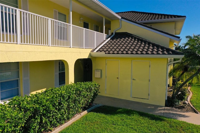 exterior space featuring a tile roof, a balcony, and stucco siding