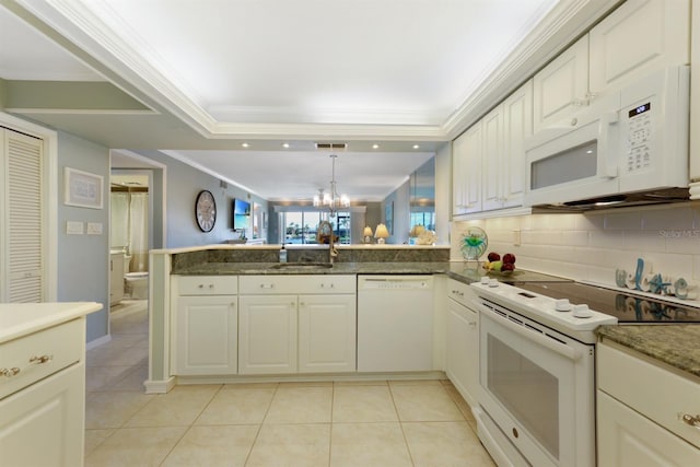 kitchen featuring an inviting chandelier, ornamental molding, a sink, white appliances, and a peninsula