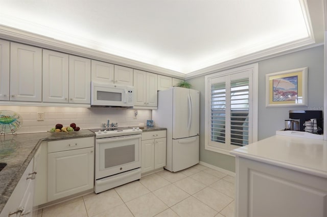 kitchen with ornamental molding, dark countertops, white appliances, and white cabinets