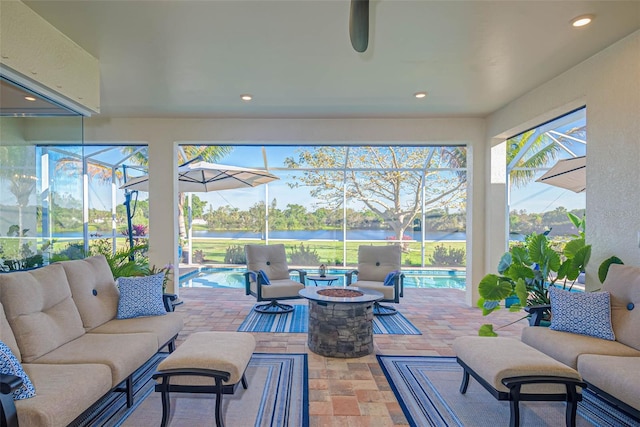 sunroom featuring ceiling fan and a water view