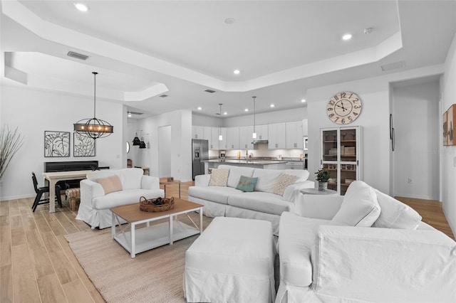 14724 Cherry Blossom Way, Punta Gorda, FL 33955 - living room featuring a chandelier, a raised ceiling, and light wood-style floors