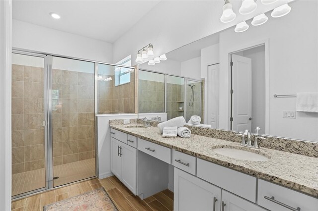 14724 Cherry Blossom Way, Punta Gorda, FL 33955 - bathroom featuring double vanity, a shower stall, a sink, and wood finish floors