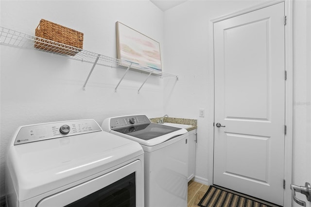 14724 Cherry Blossom Way, Punta Gorda, FL 33955 - laundry room featuring light wood-style floors, cabinet space, a sink, and washer and clothes dryer