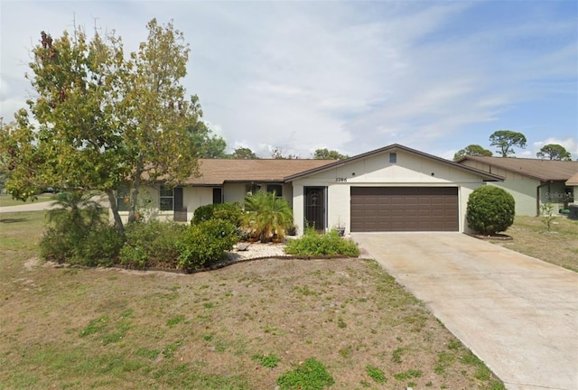 single story home featuring a garage, concrete driveway, and a front yard