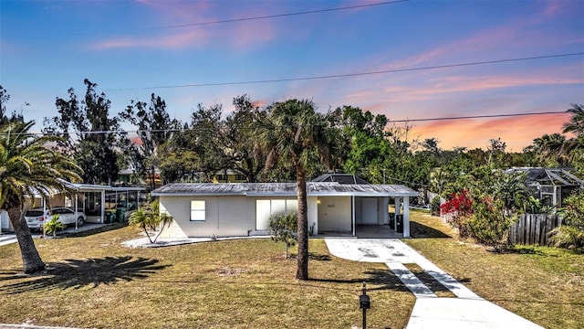 view of front of property featuring a yard, an attached carport, and driveway