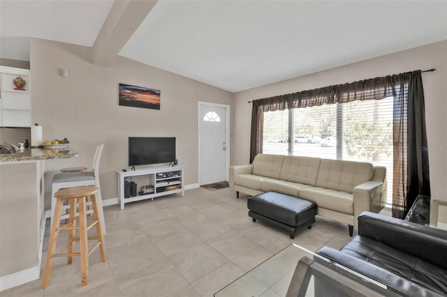 living area featuring lofted ceiling, light tile patterned floors, and baseboards