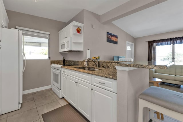 kitchen with a peninsula, white appliances, dark stone countertops, and white cabinets