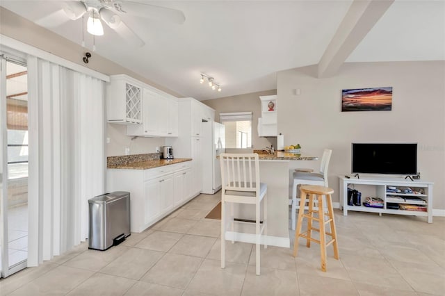 kitchen with light stone countertops, open floor plan, white cabinets, and a kitchen breakfast bar