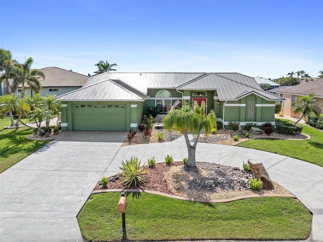 view of front facade with a garage, a front lawn, metal roof, and concrete driveway