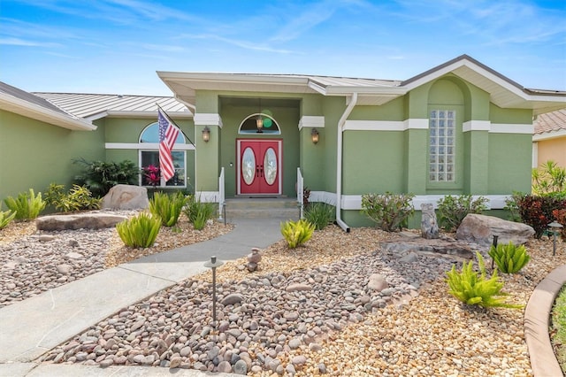 property entrance with a standing seam roof, metal roof, and stucco siding