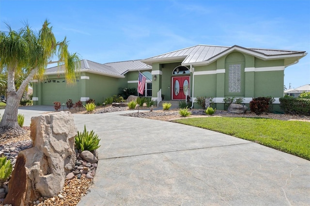 view of front of home with metal roof, driveway, an attached garage, and stucco siding