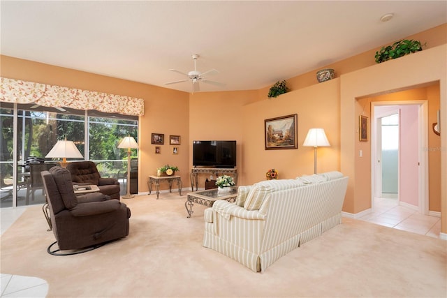 living area with a ceiling fan, light carpet, baseboards, and light tile patterned floors