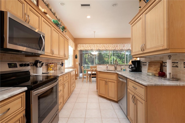 kitchen with stainless steel appliances, a sink, visible vents, hanging light fixtures, and light brown cabinetry