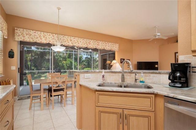 kitchen featuring stainless steel dishwasher, a sink, decorative light fixtures, and decorative backsplash