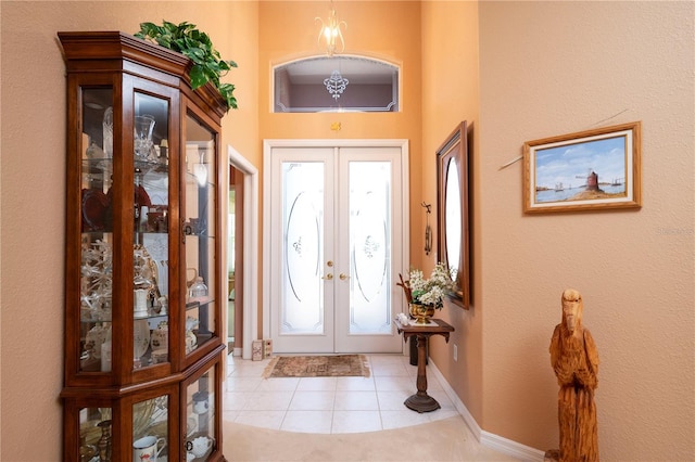 foyer entrance with baseboards, light tile patterned flooring, and french doors