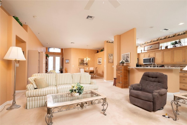 living area with light carpet, ceiling fan, visible vents, and baseboards