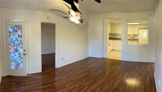 unfurnished dining area featuring ceiling fan, a textured ceiling, wood finished floors, and baseboards