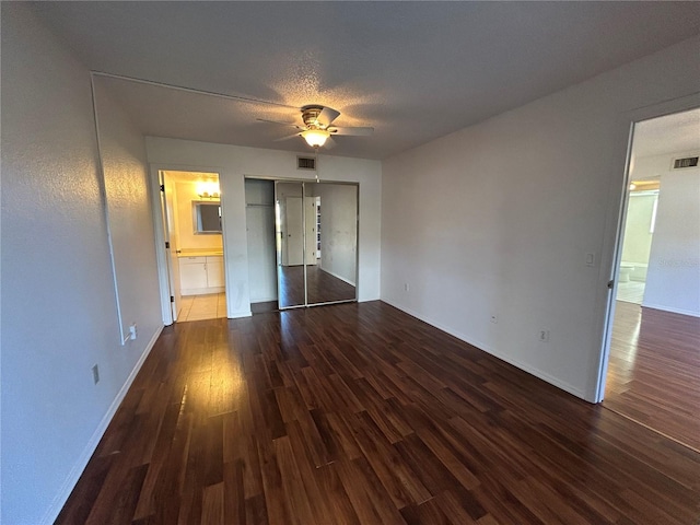 unfurnished bedroom featuring a closet, visible vents, connected bathroom, and wood finished floors