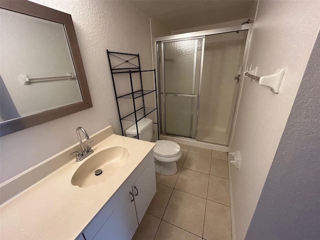 full bath featuring a stall shower, a textured wall, toilet, tile patterned flooring, and vanity