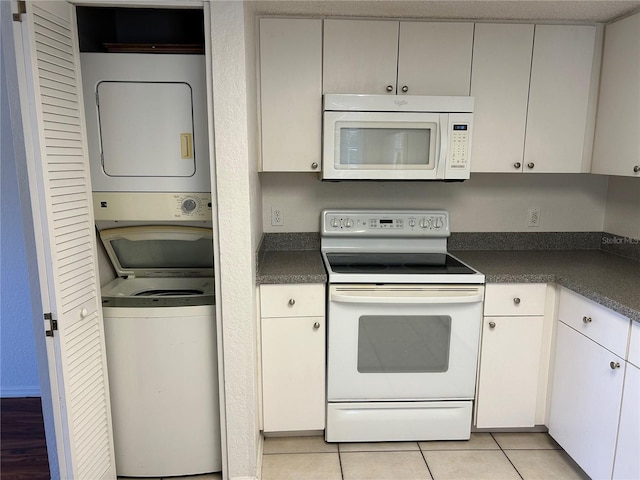 kitchen with dark countertops, white appliances, light tile patterned floors, and stacked washer and clothes dryer