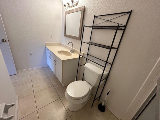 bathroom with a textured wall, vanity, toilet, and tile patterned floors