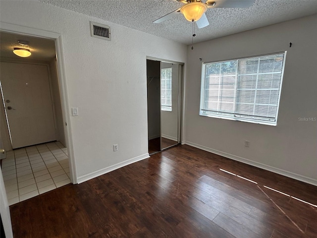 unfurnished room featuring ceiling fan, visible vents, a textured ceiling, and wood finished floors