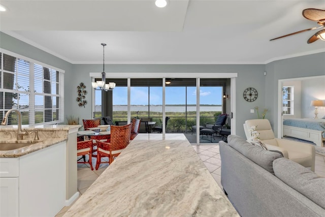 living area featuring ceiling fan with notable chandelier, light tile patterned flooring, and crown molding