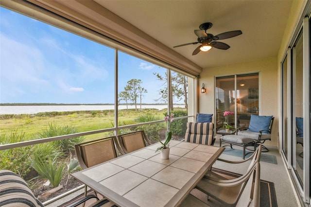 sunroom with a ceiling fan and a water view