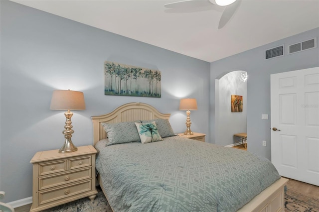 bedroom featuring visible vents, arched walkways, a ceiling fan, and wood finished floors