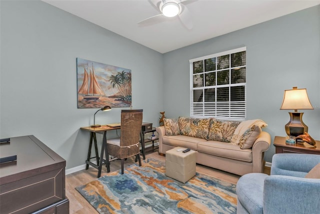 living area with baseboards, a ceiling fan, and wood finished floors