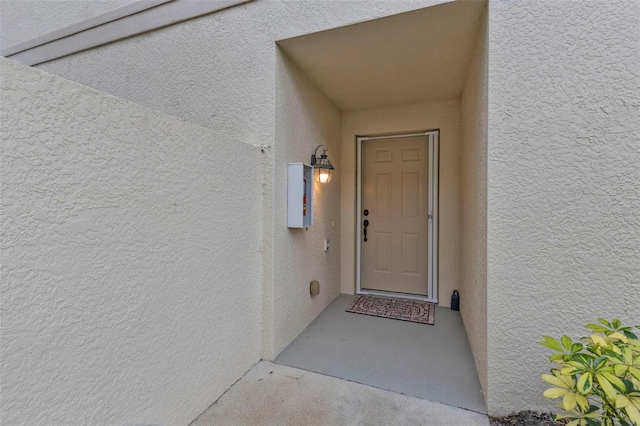 doorway to property with electric panel and stucco siding