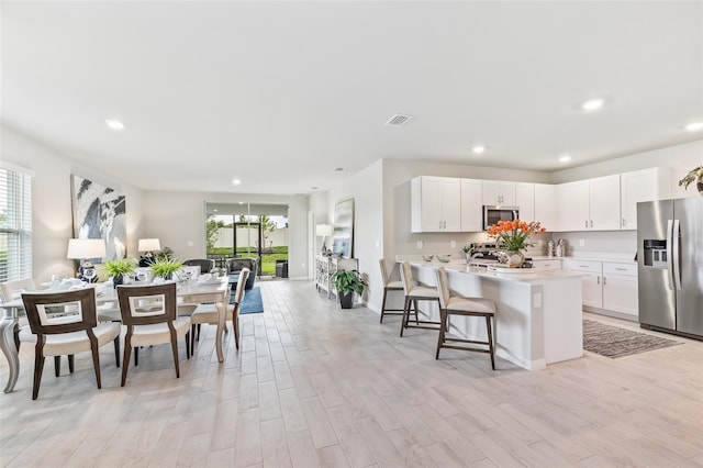 kitchen featuring light countertops, visible vents, appliances with stainless steel finishes, open floor plan, and white cabinetry