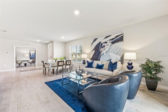 living room with baseboards, recessed lighting, visible vents, and light wood-style floors